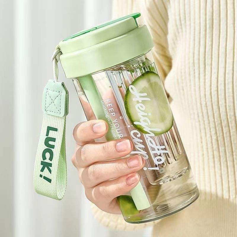 Havefy pastel green fruit infuser water bottle with a straw and carrying strap held in a hand